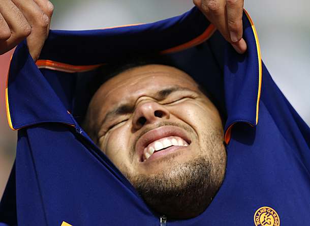 Jo-Wilfried Tsonga struggles to change his shirt during his first-round match against Edouard Roger-Vasselin. (Darko Vojinovic/AP)